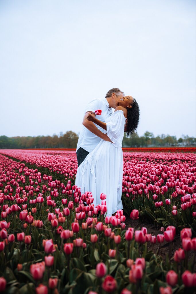 Couple embraces while standing in pink tulip fields of Kuekenhof Gardens in Amsterdam