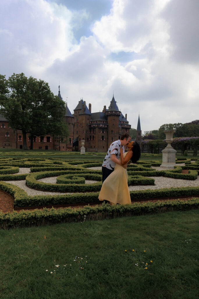 Couple embraces for a kiss in the Castle De Haar Garden in Amsterdam