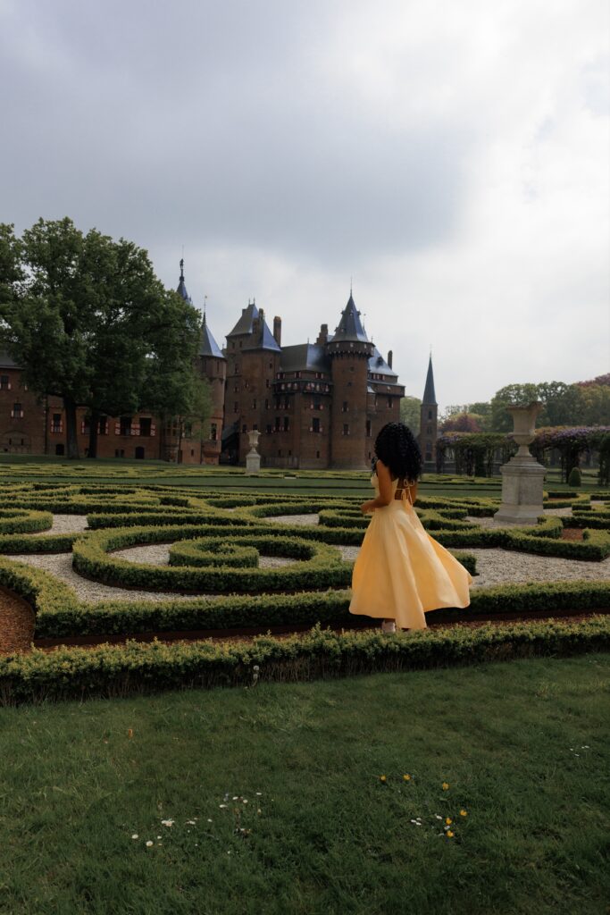 Woman in yellow dress wanders a garden at Castle De Haar Garden in Amsterdam