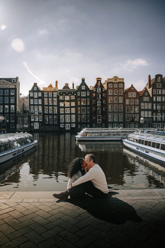 Couple embraces and sits along the river in Damrak in Amsterdam