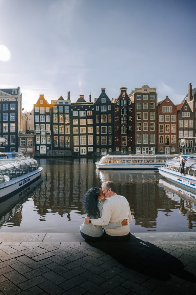 Couple embraces and sits along the river in Damrak in Amsterdam