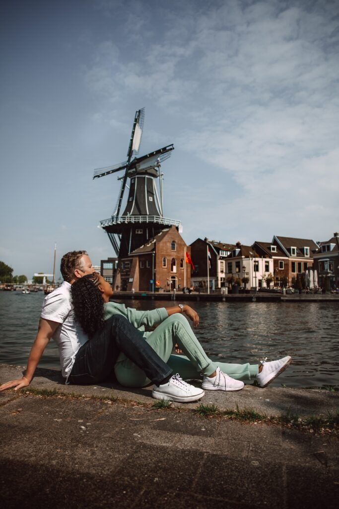 Couple relaxes by the water with a view of the Windmill De Adriaan