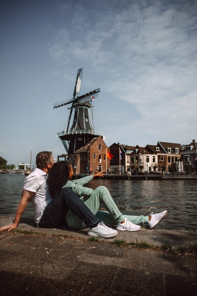 Couple relaxes by the water with a view of the Windmill De Adriaan