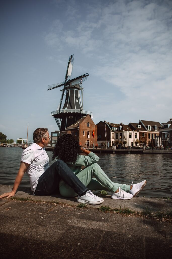 Couple relaxes by the water with a view of the Windmill De Adriaan