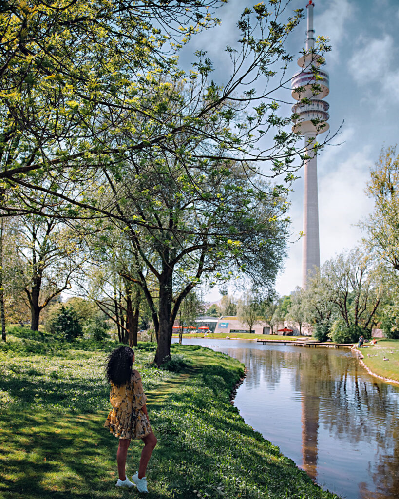 Woman stands along a river looking upon Olympic Park in Munich