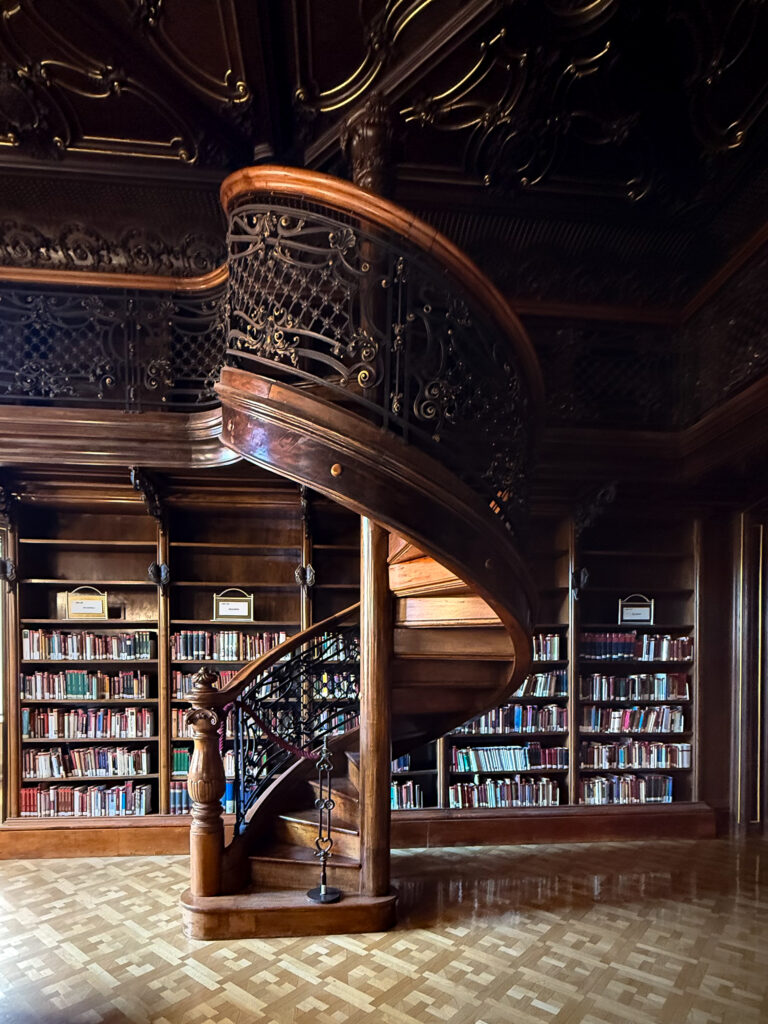 Ornate wooden spiral staircase inside Ervin Szabó Library in Budapest