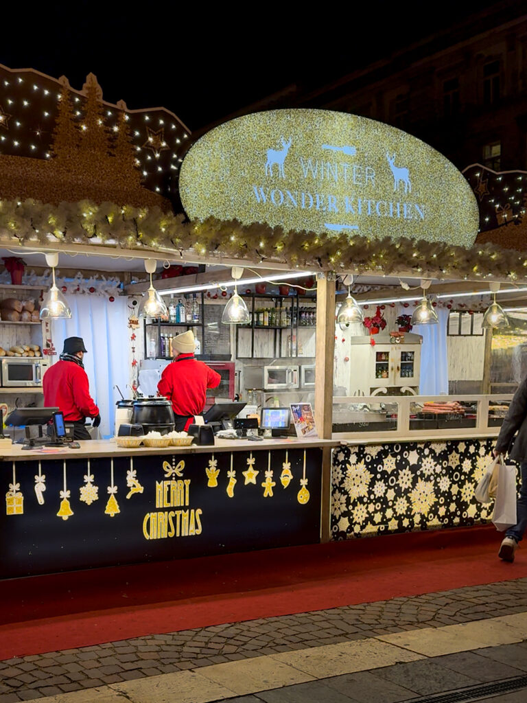 Festive Christmas food stall at Vörösmarty Square during the holiday season.